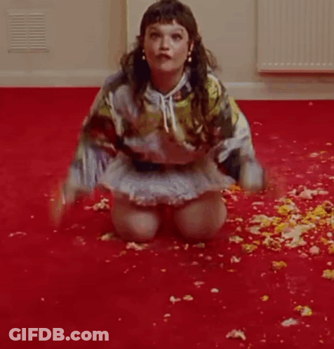 A Woman Is Kneeling On The Floor In A Room Covered In Flowers . GIF