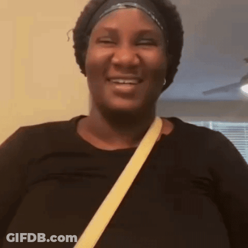 A Woman Is Laughing And Clapping Her Hands While Wearing Headphones . GIF