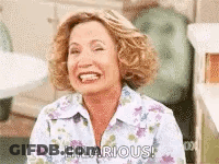 A Woman Is Laughing And Smiling While Sitting In A Chair . GIF