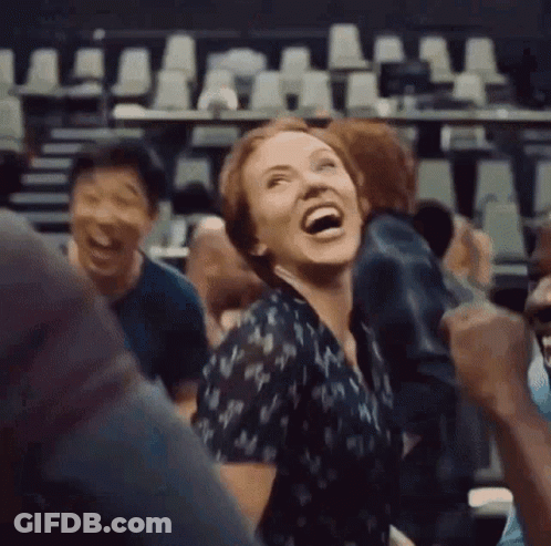 A Woman Is Laughing In A Crowd Of People In A Theater . GIF