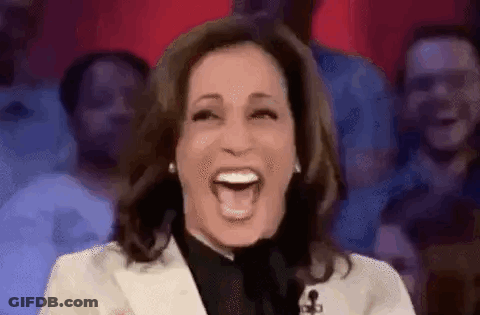 A Woman Is Laughing In Front Of A Crowd Of People . GIF