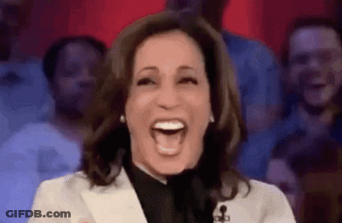 A Woman Is Laughing In Front Of A Crowd Of People . GIF