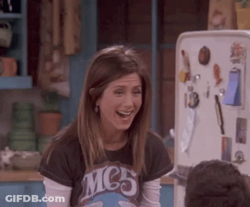 A Woman Is Laughing In Front Of A Refrigerator . GIF