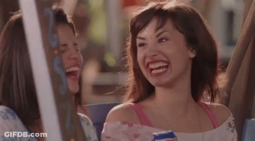 A Woman Is Laughing While Holding A Can Of Soda And Sitting Next To Another Woman . GIF