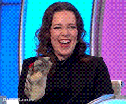 A Woman Is Laughing While Holding A Cat In Her Hand On A Television Show . GIF