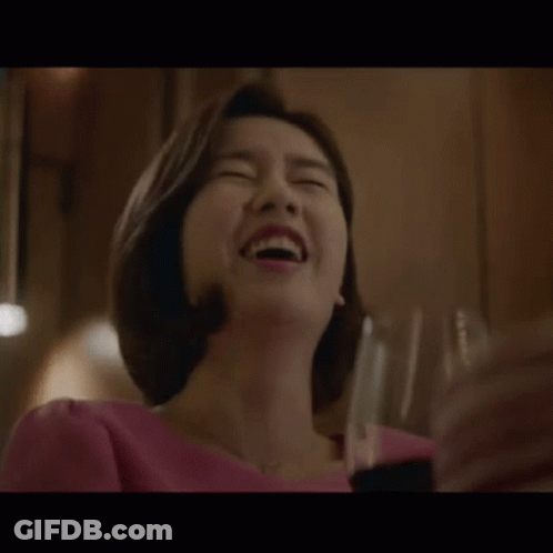 A Woman Is Laughing While Holding A Glass Of Wine In Her Hand . GIF