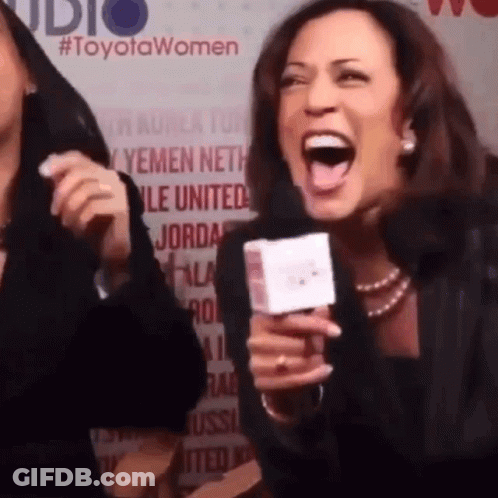 A Woman Is Laughing While Holding A Microphone In Front Of A Toyota Women Sign GIF