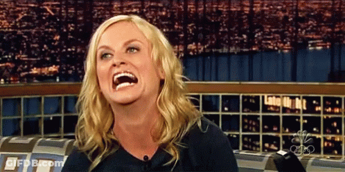 A Woman Is Laughing While Sitting In Front Of A Cbs Sign GIF