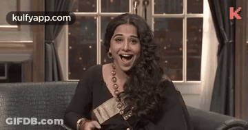 A Woman Is Laughing While Sitting On A Couch . GIF