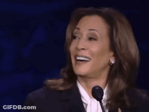 A Woman Is Laughing While Speaking Into A Microphone On A Stage . GIF