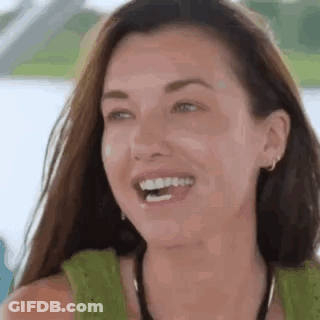 A Woman Is Laughing With Her Mouth Open And Wearing A Green Tank Top . GIF