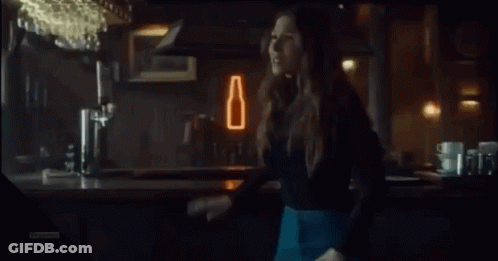 A Woman Is Laughing With Her Mouth Open In A Bar GIF