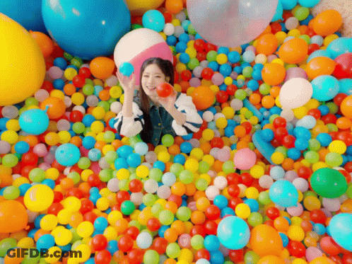 Woman Laying In Ball Pit Holding Ball GIF