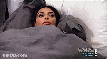 A Woman Is Laying In A Bed With A Blanket On Her Head . GIF