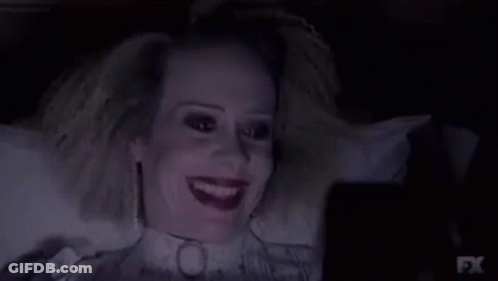 A Woman Is Laying In A Bed With A Collar Around Her Neck And Looking At A Cell Phone . GIF