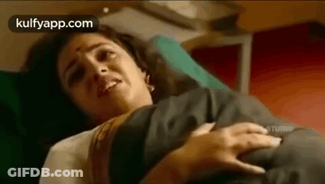 A Woman Is Laying In A Hospital Bed With A Baby In Her Arms . GIF