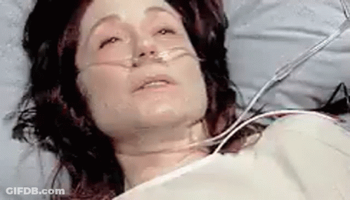 A Woman Is Laying In A Hospital Bed With An Oxygen Mask . GIF