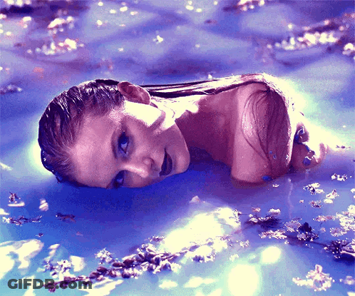 A Woman Is Laying In A Pool Of Water GIF