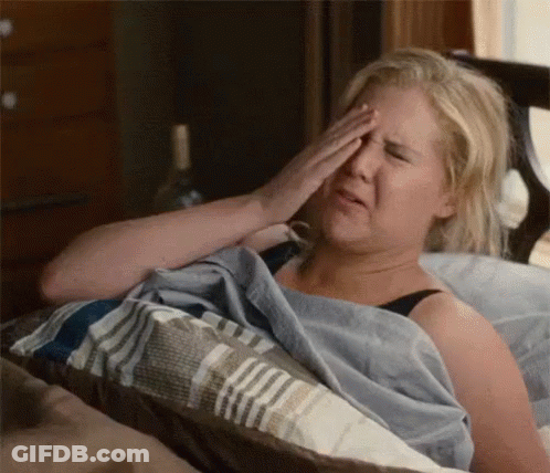 A Woman Is Laying In Bed Rubbing Her Eyes . GIF