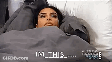 A Woman Is Laying In Bed Under A Blanket With The Words `` Im This '' Written On It . GIF