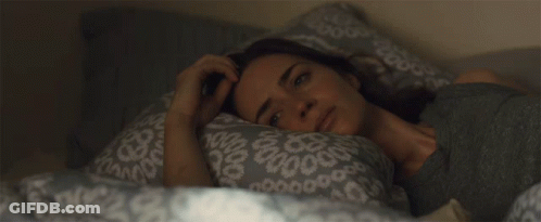 A Woman Is Laying In Bed With A Pillow That Has A Pattern Of Circles On It GIF