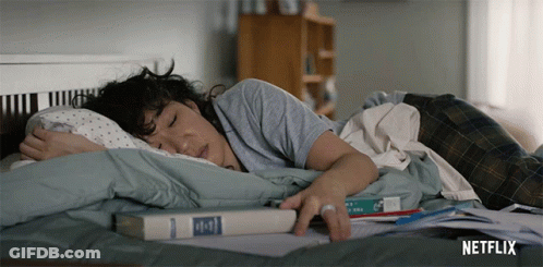 A Woman Is Laying On A Bed With A Book On Top Of Her GIF