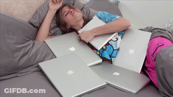 A Woman Is Laying On A Bed With Many Apple Laptops GIF