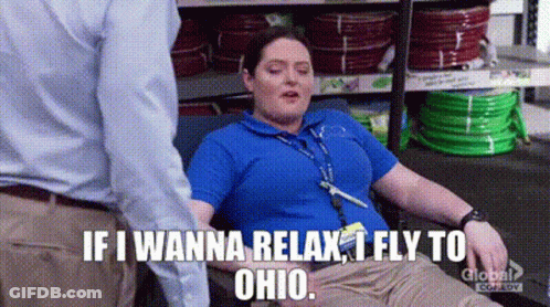 A Woman Is Laying On A Couch In A Store And A Man Is Standing Behind Her . GIF