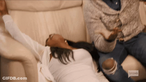 A Woman Is Laying On A Couch With Her Arms Outstretched While A Man Sits Behind Her .. GIF