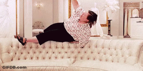 A Woman Is Laying On A White Couch With Her Feet Up GIF