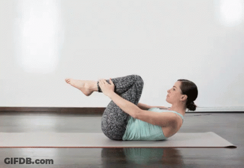 A Woman Is Laying On Her Back On A Yoga Mat With Her Legs Crossed GIF