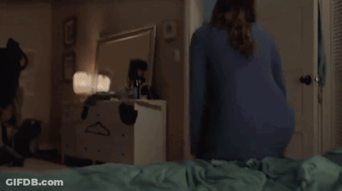 A Woman Is Laying On Her Stomach On A Bed With Her Legs Up . GIF