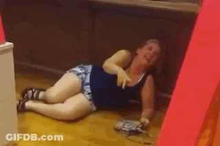 A Woman Is Laying On The Floor Laughing And Holding A Purse . GIF