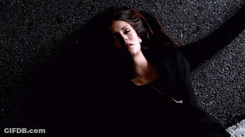 A Woman Is Laying On The Ground In A Dark Room . GIF
