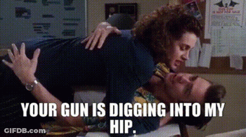 A Woman Is Laying On Top Of A Man With The Words `` Your Gun Is Digging Into My Hip '' . GIF