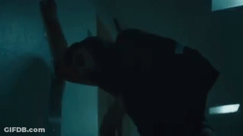 A Woman Is Leaning Against A Wall In A Dark Room In A Hospital . GIF