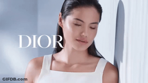 A Woman Is Leaning Against A Wall With Her Eyes Closed And The Word Dior Behind Her GIF