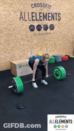A Woman Is Lifting A Barbell In Front Of A Wall That Says Crossfit Alleements GIF