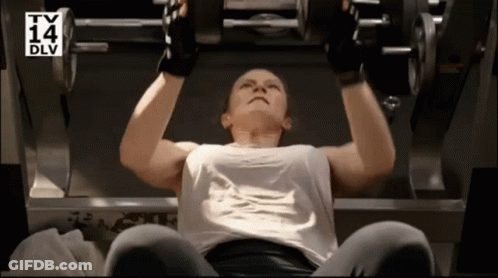 A Woman Is Lifting A Dumbbell In A Gym With A TV 14 Dlv Logo Behind Her GIF