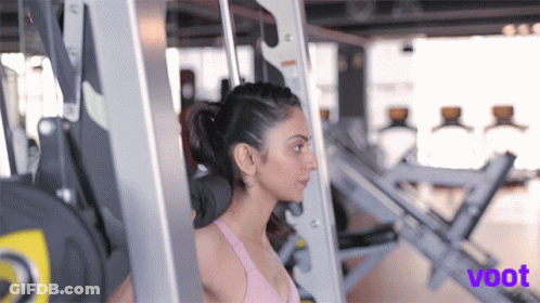 A Woman Is Lifting Weights In A Gym And The Word Voot Is On The Bottom Right GIF