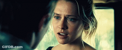 A Woman Is Looking At A Man In A Dark Room And Making A Funny Face . GIF