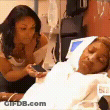 A Woman Is Looking At A Man In A Hospital Bed GIF