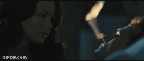 A Woman Is Looking At A Man Laying In A Bed GIF