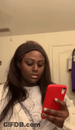 A Woman Is Looking At Her Phone And Making A Face . GIF