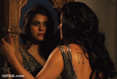 A Woman Is Looking At Her Reflection In A Mirror With A Tattoo On Her Back GIF