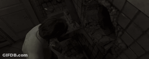 A Woman Is Looking At Herself In A Mirror In A Dark Bathroom . GIF