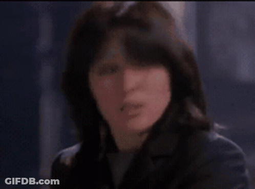 A Woman Is Looking At Herself In A Mirror In A Room GIF