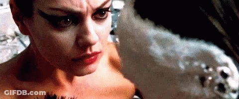 A Woman Is Looking At Herself In A Mirror While A Man Looks On . GIF