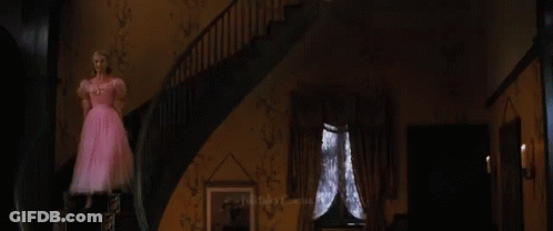 A Woman Is Looking At Herself In A Mirror While Wearing A Green Dress . GIF
