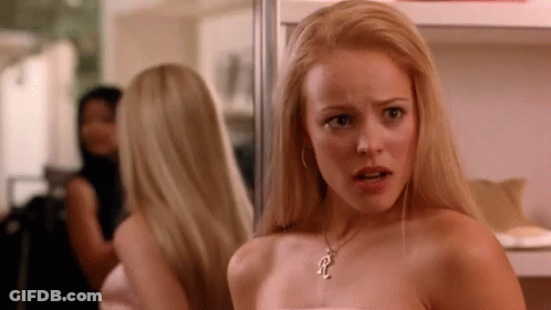 A Woman Is Looking At Herself In A Mirror While Wearing A Necklace . GIF